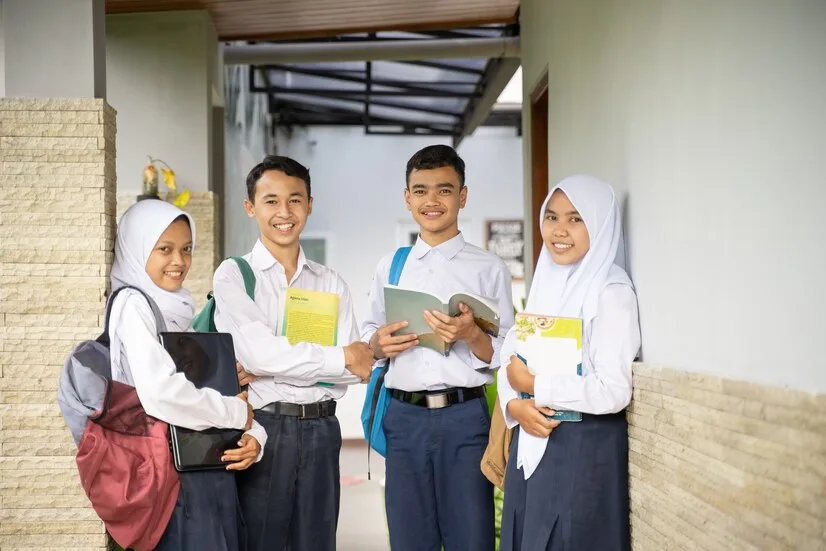 four-teenagers-junior-high-school-uniforms-stood-line-while-carrying-books-laptop_8595-23745
